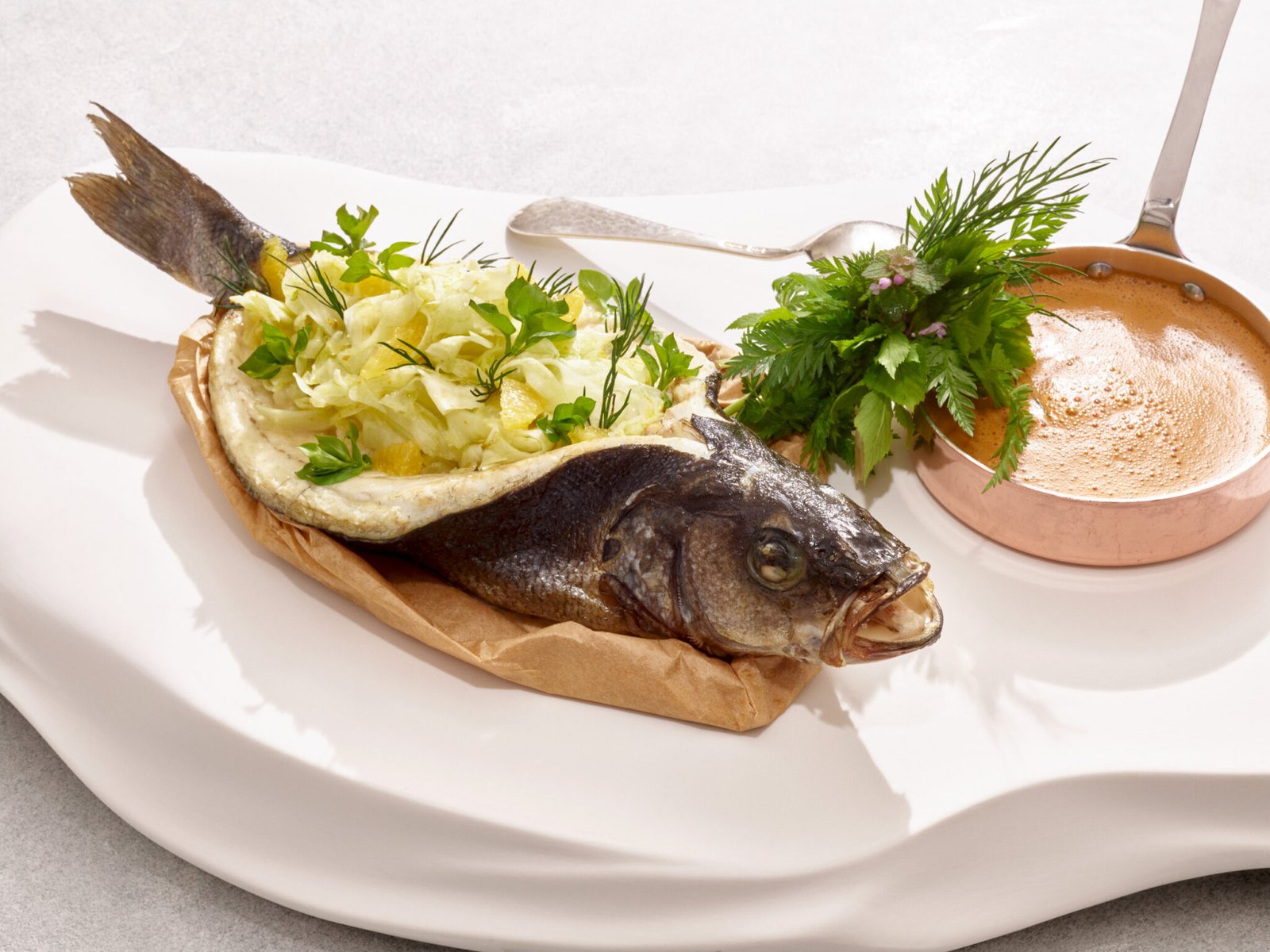 Ganzer gekochter Fisch mit Kräutern und Soße, serviert beim Männerkochkurs.