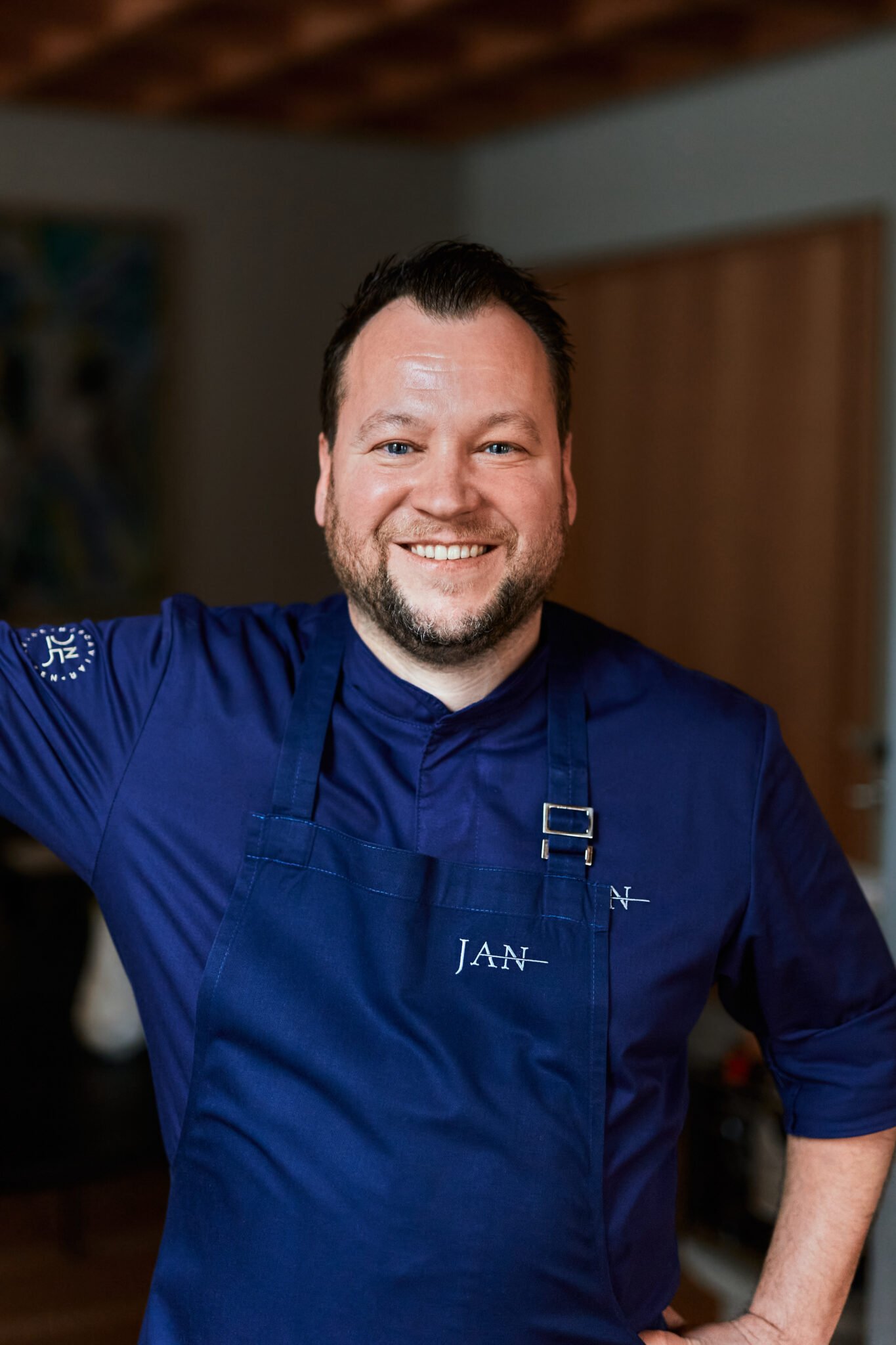Lächelnder Mann in blauer Kochjacke mit aufgesticktem "JAN".