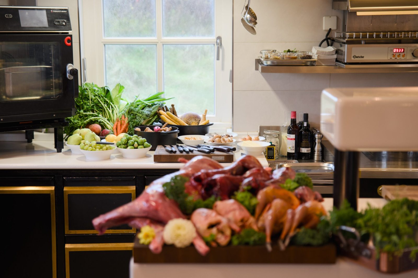 Rohes Fleisch, Geflügel, Gemüse, Obst, Wein auf der Küchentheke.
