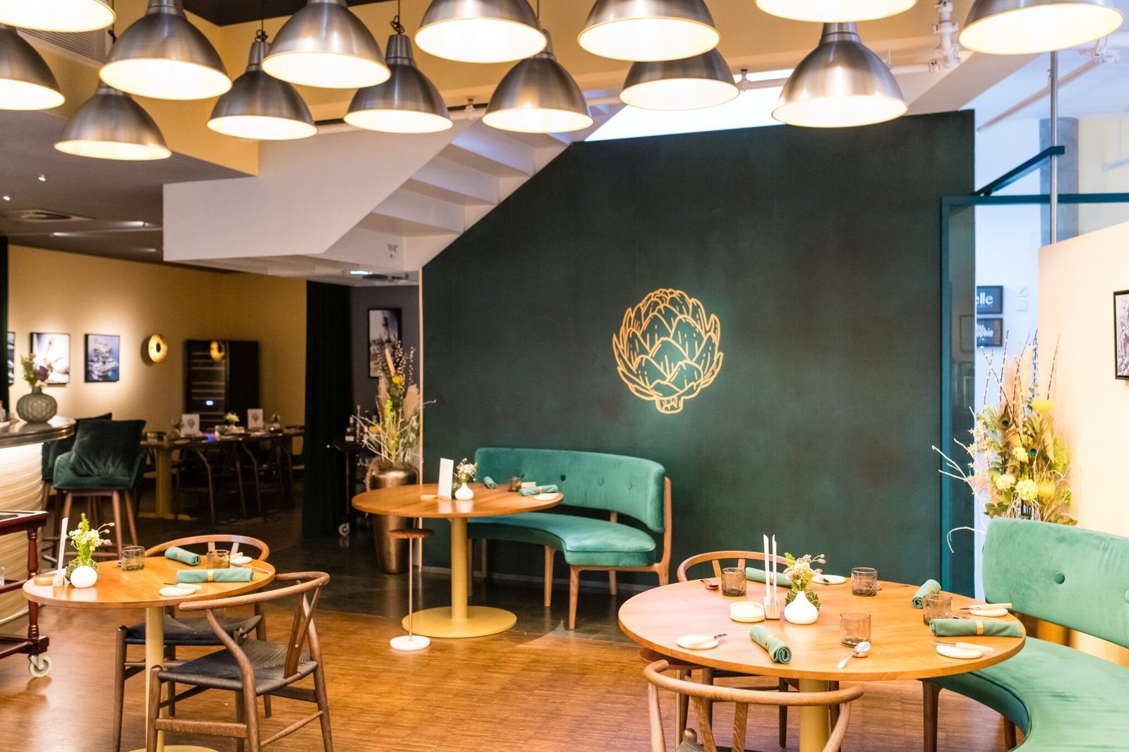 Modernes Restaurant mit Sitzen aus grünem Samt, Wandmalerei aus goldenen Artischocken und Pflanzen.