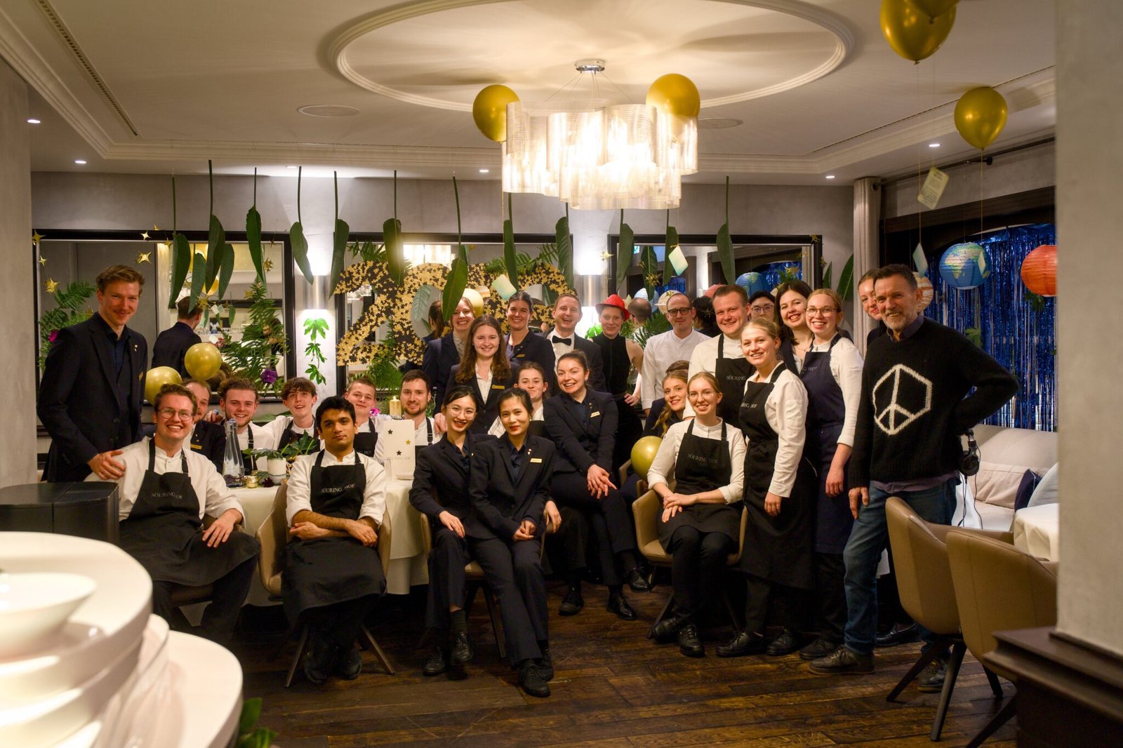 Restaurant staff and chefs pose together in festive, decorated dining room.