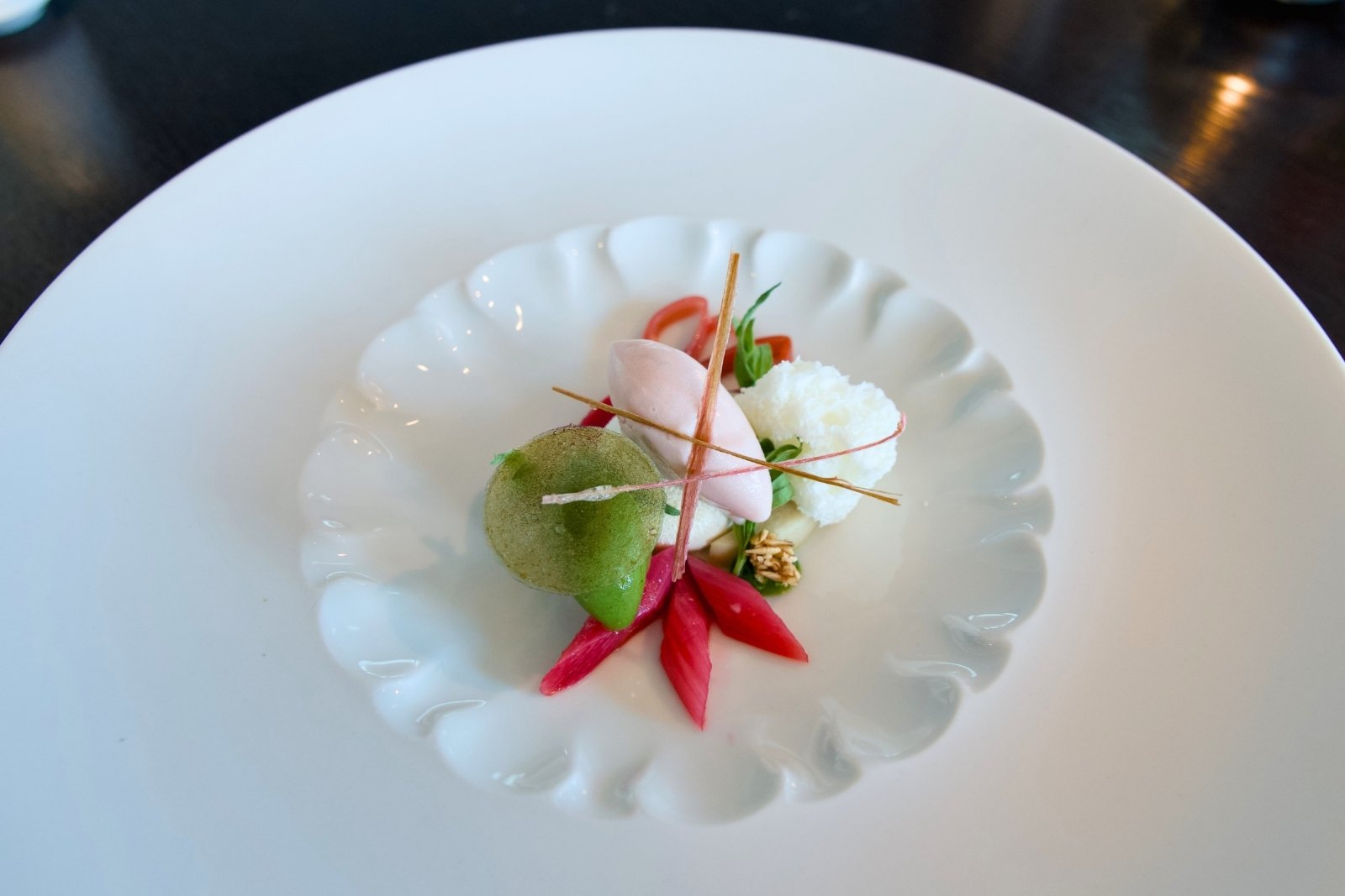 Minimalistischer Teller mit buntem Gemüse, Mousse, Krümeln und Stäbchen.
