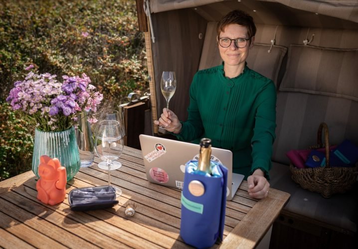 Eine Person, die sich im Söl’ring Hof auf Sylt entspannt, mit Wein und Laptop.